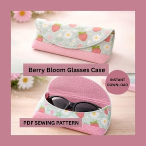 May include: A glasses case with a berry and floral pattern. The case is light blue with strawberries and white flowers on the top flap. The bottom is pink with white polka dots. The text "Berry Bloom Glasses Case" is visible.