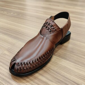 May include: Brown leather sandal with a woven design on the vamp and upper. The sandal has a slingback strap and a black sole. The open-toe design and the woven details give the sandal a unique look. The sandal is made of leather.