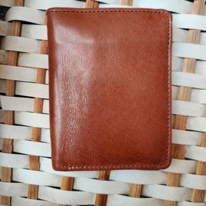 Cartera plegable de cuero marrón con múltiples ranuras para tarjetas, compartimento para efectivo y bolsillo para monedas.