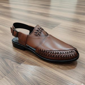 May include: Brown leather sandal with woven detailing on the vamp and upper. The sandal features an adjustable ankle strap with a buckle closure and a black sole. The shoe is designed for comfort and style.