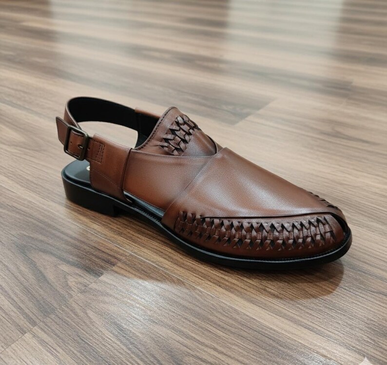 May include: Brown leather sandal with woven detailing on the vamp and upper. The sandal features an adjustable ankle strap with a buckle closure and a black sole. The shoe is designed for comfort and style.