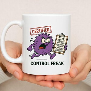 May include: White ceramic mug featuring a cartoon purple monster graphic, the word "CERTIFIED" in a red rectangle, and the words "CONTROL FREAK" below. The monster holds a clipboard with a to-do list.