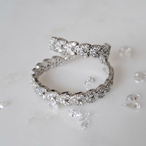 Puede incluir: Dos anillos de plata con un diseño de hoja y piedras de circonita cúbica transparentes. Los anillos están apilados uno encima del otro.