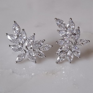 May include: A pair of silver earrings with a cluster of clear marquise-shaped stones arranged in a leaf-like design.