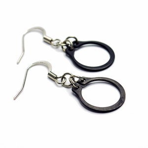 May include: A pair of black hoop earrings with silver hooks. The hoops are simple and circular.