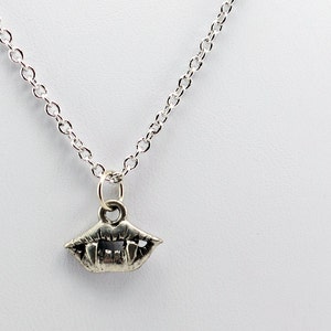 May include: A silver necklace with a small, detailed pendant shaped like a set of fangs.