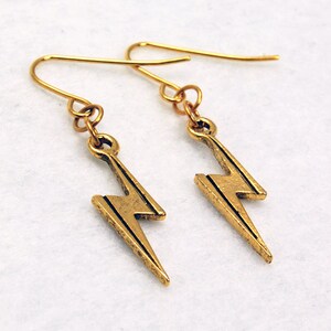 May include: Gold lightning bolt earrings with a simple design. The earrings are made of metal and have a hook fastening.