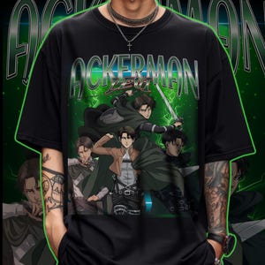 May include: Black t-shirt featuring a graphic of anime characters with the text "ACKERMAN LEVI" in a retro style. The design includes images of characters in action poses with swords and capes, set against a green background.