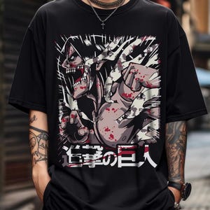 May include: Black t-shirt featuring a graphic of a muscular, screaming figure with a detailed face and open mouth. The design includes red and gray accents, with Japanese text at the bottom. The shirt has short sleeves.
