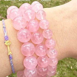 May include: Three pink rose quartz bracelets with beads of different sizes. The bracelets are 11mm, 10mm, and 8mm in diameter.