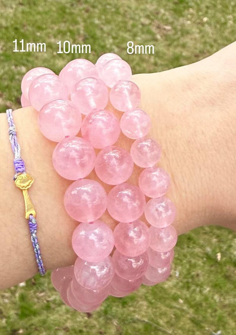 May include: Three pink rose quartz bracelets with beads of different sizes. The bracelets are 11mm, 10mm, and 8mm in diameter.