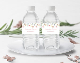 May include: Two clear plastic water bottles with personalised labels. The labels feature a watercolour floral design with pink, yellow, and blue flowers. The text on the labels reads "Jessica Smith Baby Shower".