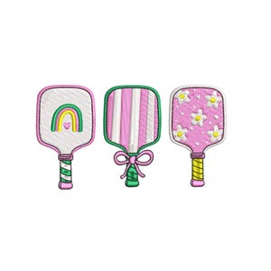 Puede incluir: Tres palas de pickleball bordadas. Las palas presentan un arcoíris, rayas rosas y blancas y flores blancas con centros amarillos. Cada pala tiene un diseño de mango diferente con detalles en verde, rosa y amarillo. Las palas están sobre un fondo blanco.