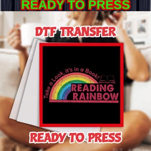 May include: A black square DTF transfer with a rainbow design and the words "READING RAINBOW". The text "Take a Look, it's in a Book!" arches over the rainbow. The words "READY TO PRESS" are at the top and bottom.