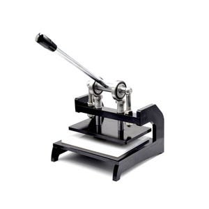 Könnte beinhalten: Eine manuelle Presse in Schwarz und Silber mit langem Griff. Die Maschine hat eine rechteckige Basis mit einem weißen Pad und einer schwarzen Deckplatte. Der Griff ist schwarz und der Rest der Maschine ist silberfarben.