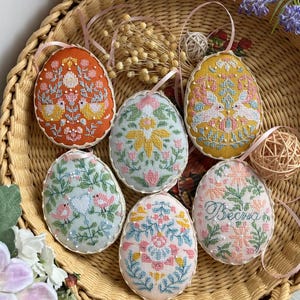 Può includere: Sei uova di Pasqua ricamate in un cesto di vimini. Le uova sono decorate con motivi floreali, uccelli e la parola "Весна" in scrittura cirillica.