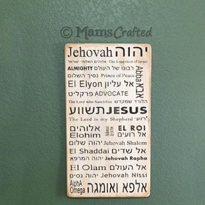 May include: A wooden sign with the word "Jehovah" in Hebrew and English, along with other Hebrew words and their English translations. The sign is a beige color with black lettering.