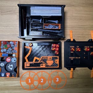 May include: A collection of black and orange game accessories, including storage boxes, dice, tokens, and target markers. The set includes a game board, dice, and various game pieces. The accessories are arranged on a wooden surface.