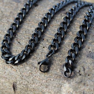 May include: A black chain necklace with a curb link design. The chain is made of metal and has a shiny finish.