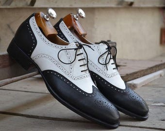 May include: Black and white leather Oxford shoes with brogue detailing and lace-up closure.