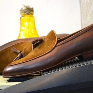 Peut inclure: Mocassins en cuir marron avec un d&eacute;tail en su&egrave;de &agrave; glands. Les mocassins ont une tige en cuir marron et un embout en su&egrave;de marron. Les mocassins sont sur une semelle en cuir marron.