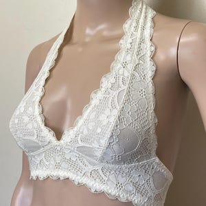 Pu&ograve; includere: Reggiseno all'uncinetto color avorio con bordo smerlato. Il reggiseno presenta un delicato motivo floreale e un design morbido e confortevole. Questo capo di lingerie offre un look elegante e femminile.