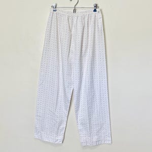 May include: White pajama pants with a small, light gray floral pattern. The pants have an elastic waistband and a relaxed fit.