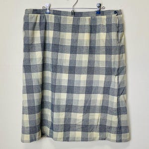 May include: A plaid skirt in a cream and blue color scheme. The skirt has a straight silhouette and a simple design.