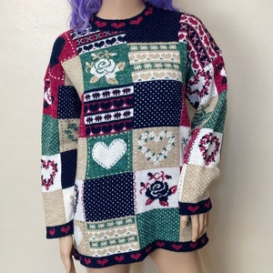 May include: A colorful patchwork sweater with a variety of patterns, including hearts, flowers, and wreaths. The sweater is made of a soft, knitted fabric and has a relaxed fit.