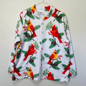 May include: White zippered jacket with a festive print of red cardinals, green pine branches, and red berries.