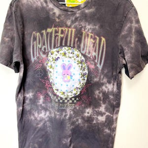 May include: A black tie-dye t-shirt with a colorful Grateful Dead logo and a cartoon bunny. The logo includes the text "Grateful Dead" and "Summer Tour 1987".