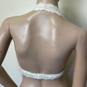 Pu&ograve; includere: Top all'uncinetto color avorio con un delicato design floreale. Il top presenta un collo all'americana e una schiena scoperta, fissata con una chiusura a gancio e occhiello. Il bordo in pizzo aggiunge un tocco di eleganza.