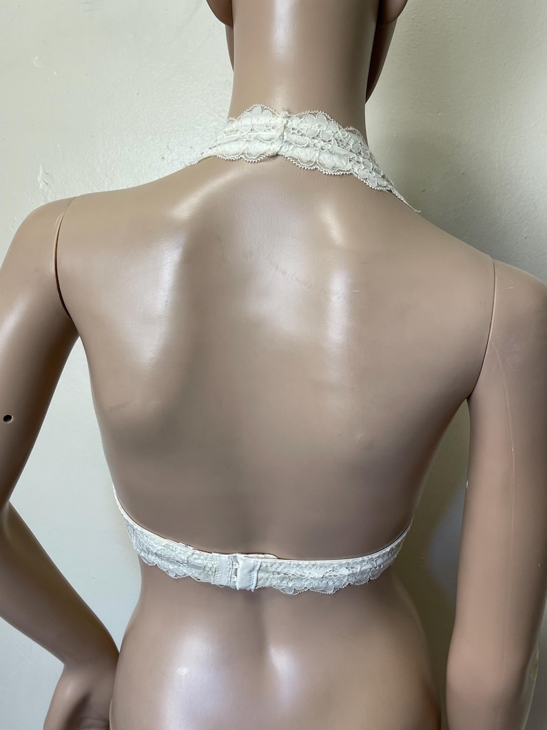 Pu&ograve; includere: Top all'uncinetto color avorio con un delicato design floreale. Il top presenta un collo all'americana e una schiena scoperta, fissata con una chiusura a gancio e occhiello. Il bordo in pizzo aggiunge un tocco di eleganza.