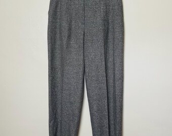 Peut inclure: Pantalon en tweed gris avec fermeture boutonnée et zippée, et passants de ceinture. Le pantalon est suspendu à un cintre sur fond blanc. Le pantalon a deux poches avant et une jambe droite.