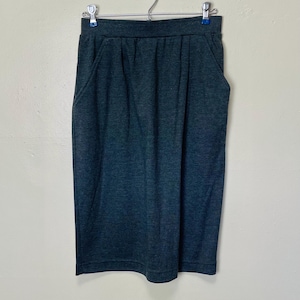 May include: A dark gray midi skirt with a straight silhouette and two pockets. The skirt is made of a soft, stretchy fabric.