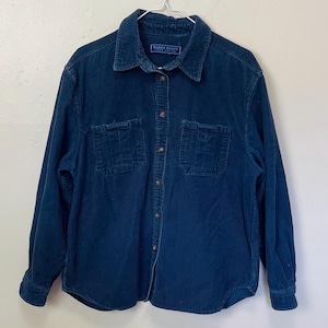 Puede incluir: Una camisa de pana azul oscuro con dos bolsillos en el pecho y botones. La camisa tiene mangas largas y cuello. La marca "KAREN SCOTT" es visible en el cuello.