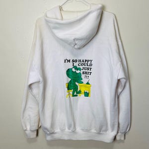 May include: White hooded sweatshirt with a graphic of a green frog at a desk with the text "I'M SO HAPPY I COULD JUST SHIT !!!". The sweatshirt is hanging on a hanger.