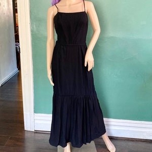 May include: A black maxi dress with a fitted bodice and a flowing skirt. The dress has a simple, elegant design and is perfect for a special occasion.