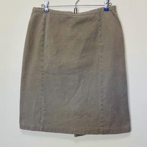 May include: A brown, knee-length skirt with a straight cut and a simple design.