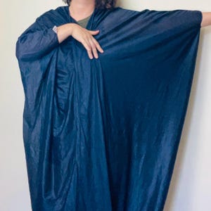 May include: A dark blue, flowing garment with long sleeves. The fabric has a slight sheen, and the garment drapes loosely. The style appears to be a wrap or kimono-style design. The overall look is elegant and comfortable.