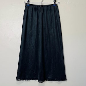 May include: A black slip skirt with a lace trim. The skirt is made of a smooth, silky fabric.