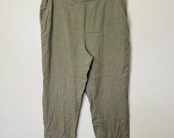 May include: Olive green linen pants with a cropped length and a decorative crochet trim at the hem. The pants have a relaxed fit, pockets, and are hanging on a hanger against a white background.