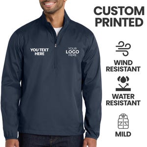 May include: Navy blue wind and water-resistant jacket with a quarter-zip closure. The jacket features the text "YOU TEXT HERE" and "YOUR LOGO HERE" on the front. The image also includes the words "CUSTOM PRINTED", "WIND RESISTANT", "WATER RESISTANT", and "MILD".