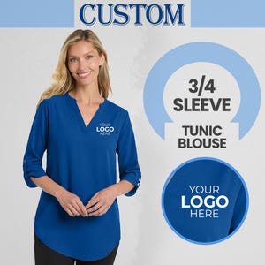 May include: A royal blue tunic blouse with 3/4 sleeves and a V-neck. The blouse has a curved hemline and a small logo area. The text "CUSTOM" is at the top. The text "3/4 SLEEVE TUNIC BLOUSE" is on the right side. The text "YOUR LOGO HERE" is on the blouse.