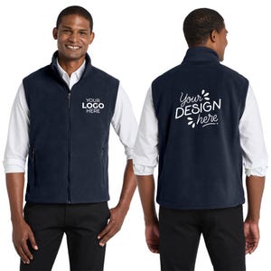 May include: Navy blue fleece vest with a full zipper and a mock neck collar. The front of the vest has the text "YOUR LOGO HERE" printed in white. The back of the vest has the text "Your DESIGN here" printed in white.