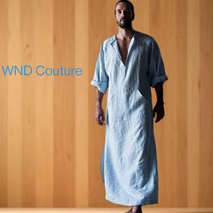 May include: A light blue long-sleeved tunic with a V-neckline and a single pocket on the left side. The tunic is made of a lightweight fabric and has a relaxed fit. WND Couture is printed in blue text at the top of the image.