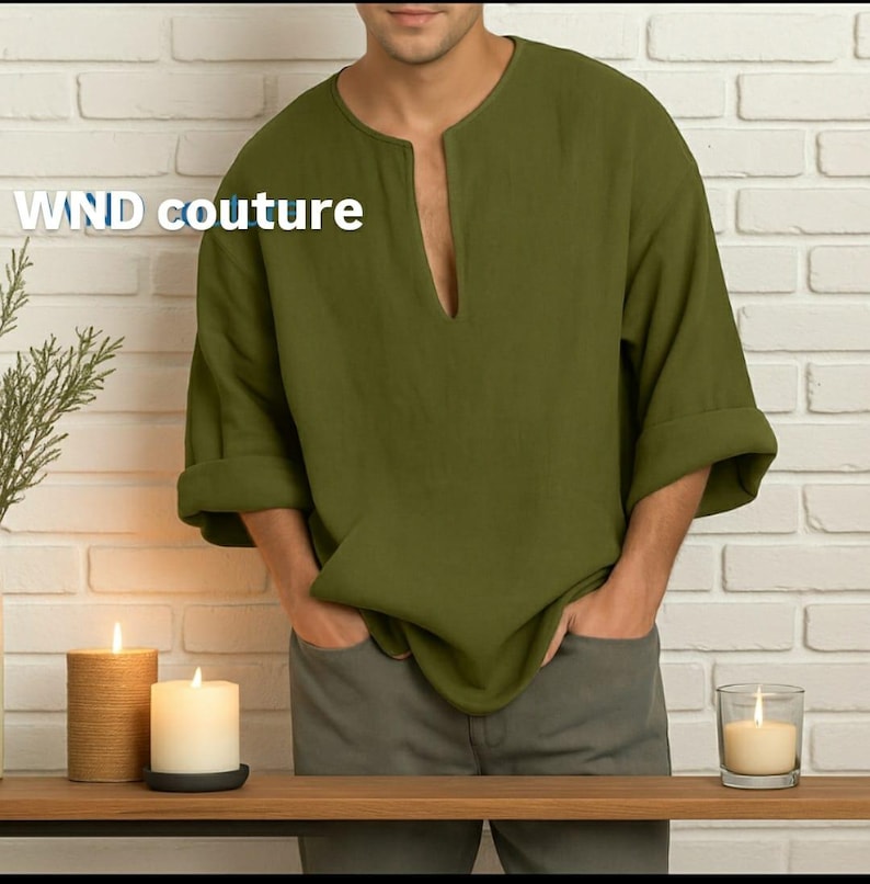 May include: Olive green linen shirt with a V-neck and rolled-up sleeves. The shirt has a relaxed fit and is paired with gray pants. The text "WND couture" is printed on the shirt. The background includes candles and a brick wall.