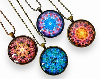 May include: Four necklaces with round pendants featuring colorful mandala designs. The pendants are made of glass and have a bronze-colored metal frame. The necklaces are on a white background.