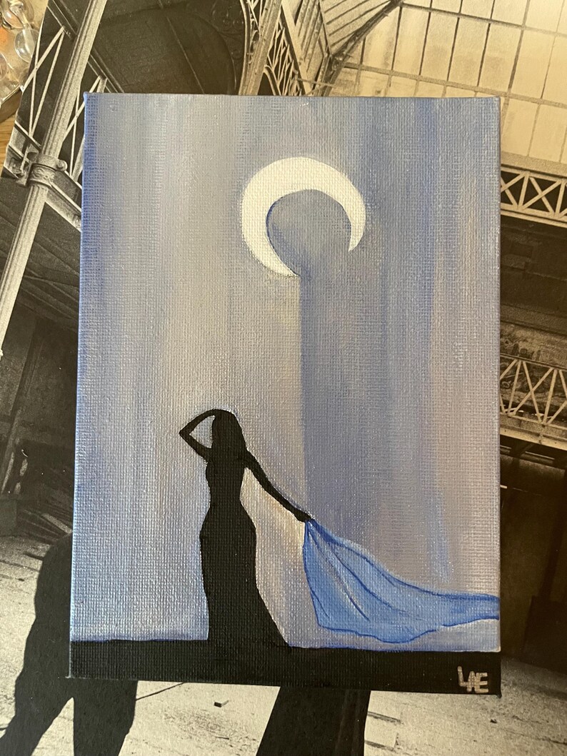 May include: A painting of a woman in a long black dress with a blue scarf flowing behind her. The woman is silhouetted against a light blue background with a white crescent moon in the upper right corner.