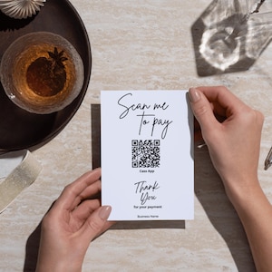 Könnte beinhalten: Eine weiße Karte, die von zwei Händen gehalten wird, mit dem Text "Scan me to pay" und einem QR-Code. Unter dem Code stehen die Worte "Thank You" und "for your payment". Die Karte ist für die Cass App.